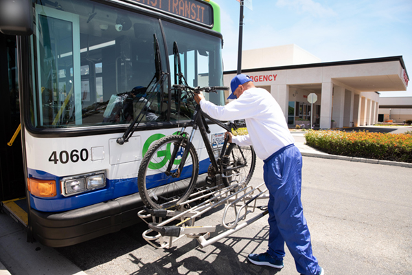 man placing bike on innner rack of bus
